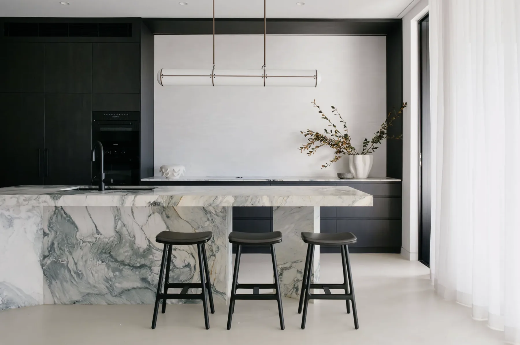 STUDIO BELLE open-plan kitchen with dark cabinetry and European stone